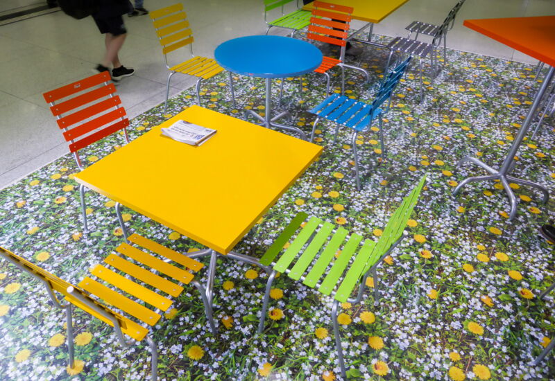Auf der künstlerischen Bodenbeschriftung werden Tische und Stühle von Schubiger Möbel platziert